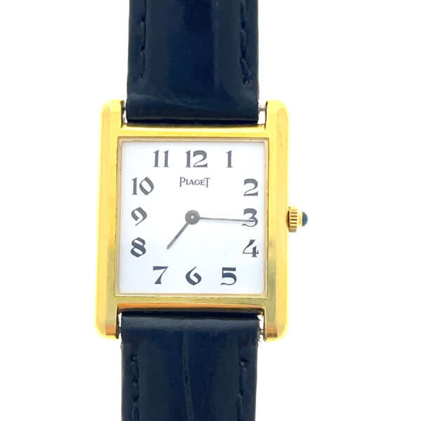 An estate Piaget Tank watch featuring an 18 karat yellow gold square case, white dial, and black leather strap