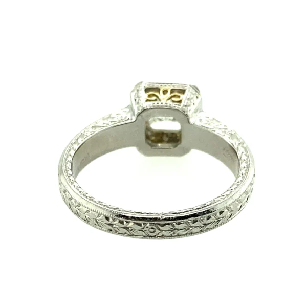 One estate platinum halo engagement ring by Michael Beaudry with a center radiant-cut diamond weighing 1.01 carats and 24 round brilliant diamonds set in the halo and in the band. The under carriage has an 18 karat yellow gold filigree accent