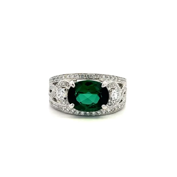 One estate 14 karat white gold ring with an oval faceted green tourmaline weighing 2.95 carats and round brilliant accent diamonds weighing 0.55 carat total weight with a figure eight design in the shoulders and a carved wheat leaf design in the remainder of the band
