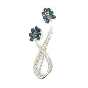 an estate 14 karat white gold floral motif brooch with 12 4x3mm natural blue oval sapphire's approximately 3.00 total carat weight, 2 round natural blue sapphires 2.5mm, and 26 single cut diamonds approximately 0.75 total carat weight with matching H/I color and VS clarity. The blue sapphires are the petals and blossoms while the diamonds are the stems. The brooch is complete with a locking safety catch.