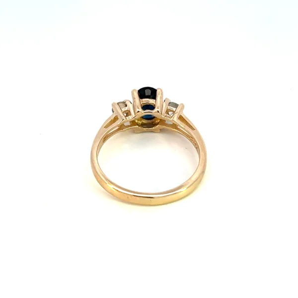 One estate 14 karat yellow gold three-stone ring with a center 0.97 carat oval faceted blue sapphire and 2 round brilliant diamonds weighing 0.25 carat total weight