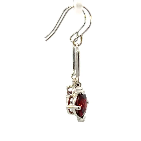 One estate pair of 14 karat white gold drop earrings with each earring featuring a thin polished silver bar accent that drops to an 8mm round checkerboard-faceted garnet in a four-prong setting