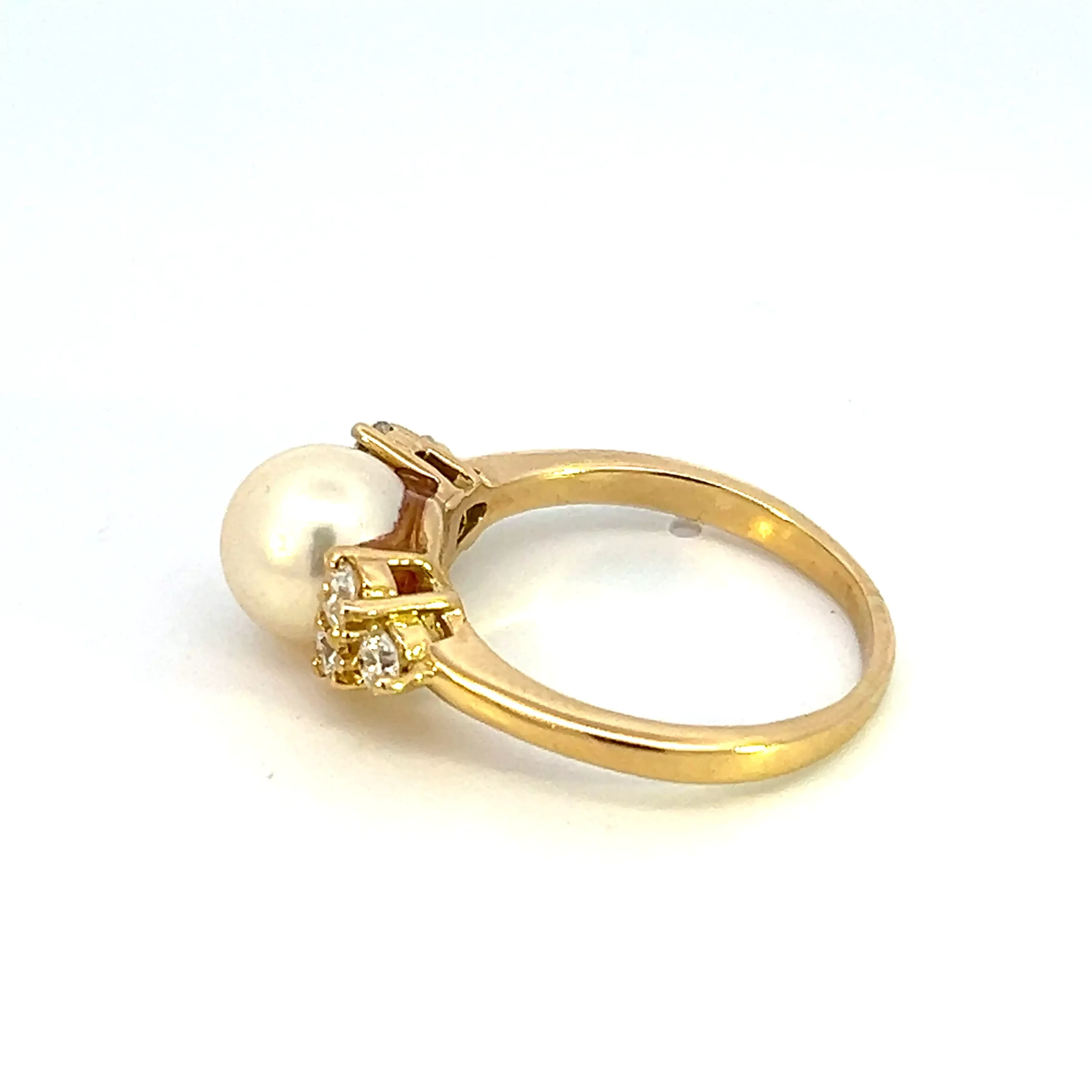 One estate 18 karat yellow ring with a 8.5mm cream-colored cultured pearl with 6 round brilliant-cut diamonds weighing 0.50 carat total weight in a cluster of 3 on each side of the pearl
