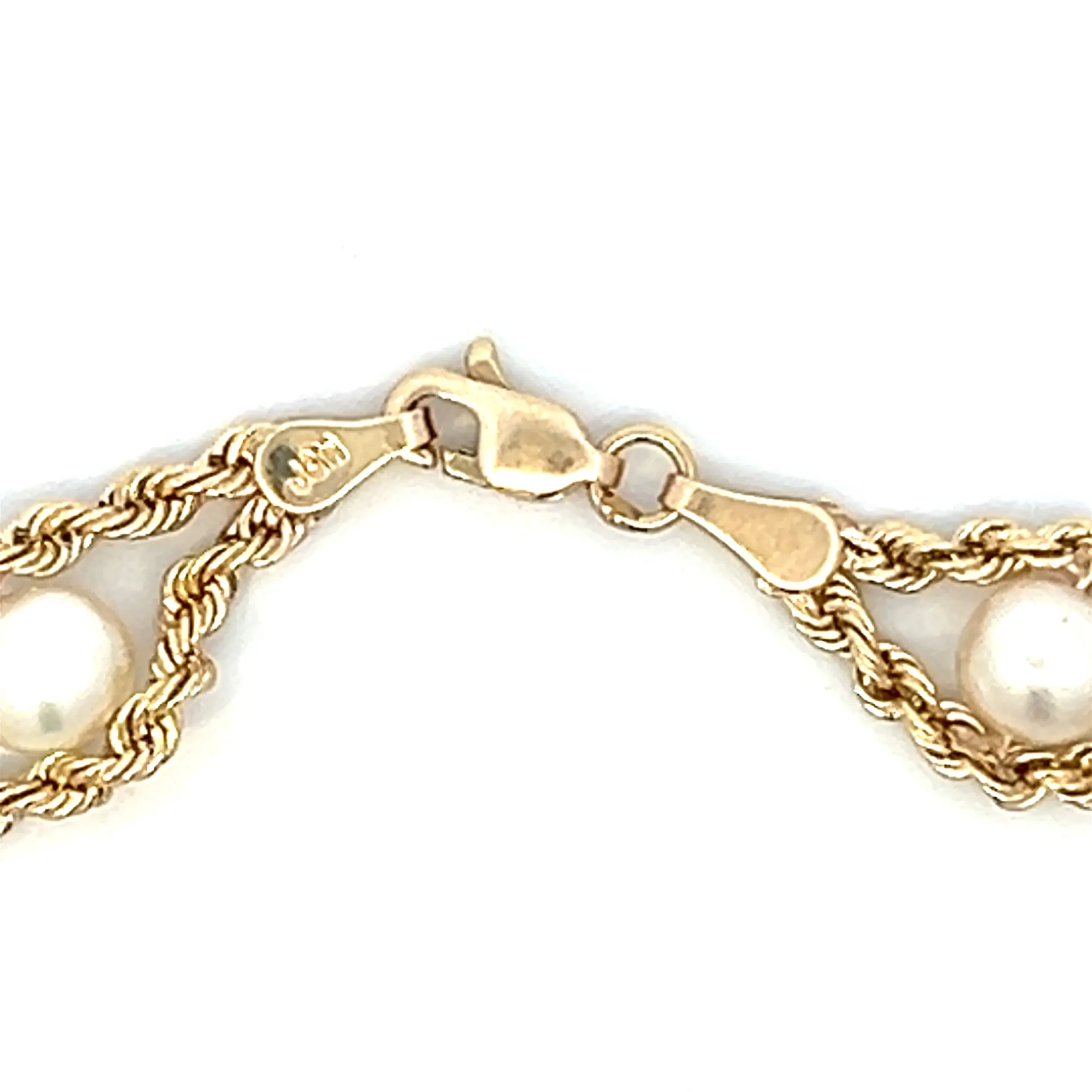 One estate 10 karat yellow gold twin rope chain bracelet containing 8 freshwater cultured white pearls measuring 5.5mm each. The rope chains join between each pearl and then divide to go around each pearl. The bracelet measures 7" long and has a lobster claw clasp.