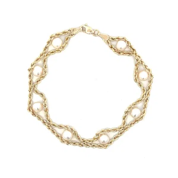 One estate 10 karat yellow gold twin rope chain bracelet containing 8 freshwater cultured white pearls measuring 5.5mm each. The rope chains join between each pearl and then divide to go around each pearl. The bracelet measures 7" long and has a lobster claw clasp.