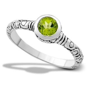 A sterling silver ring from the Royal Bali Collection by Samuel with a round faceted peridot in a bezel setting and a Bali-inspired carved design in the band