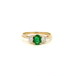 One estate vintage 14 karat yellow gold three-stone ring with a center oval emerald measuring 6x4mm and 2 round brilliant diamonds weighing 0.30 carat total weight. The ring is from the 1970s.