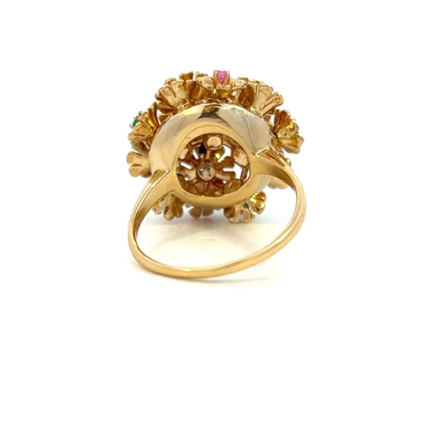 One estate vintage flower ring crafted from 18 karat yellow gold. The head of the ring has 11 distinct flower shapes each set with a different 2mm round stone including 1 diamond, 3 emeralds, 3 blue sapphires, and 4 rubies.
