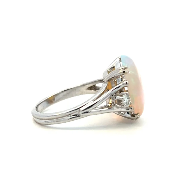 One estate 14 karat white gold opal ring set with a slightly oval mostly round cabochon opal with light blue/green color measuring 15.4x14mm. Each shoulder of the ring features a round brilliant diamond and the ring has a split-shank band.