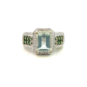 One estate sterling silver green quartz ring featuring emerald-cut green quartz inside a halo of silver bead work. The band features a double row of round green cubic zirconia with silver beadwork also on each edge of the cubic zirconia.