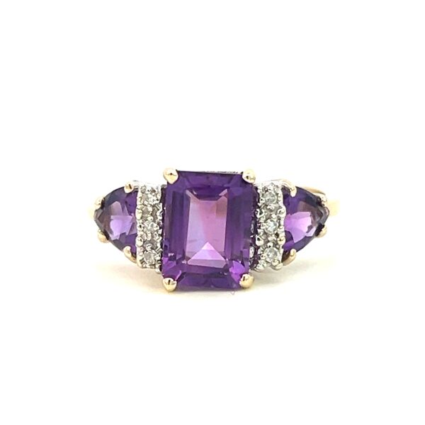 One estate vintage 10 karat yellow and white gold amethyst and diamond ring containing a center emerald-cut amethyst measuring 8x6mm and 2 trillion-cut amethyst measuring 5mm each. In between the center amethyst and each side amethyst are 3 round brilliant diamonds with all 6 diamonds weighing 0.06 carat total weight in white gold settings with the remainder of the ring being yellow gold. The ring is vintage from the 1970s.