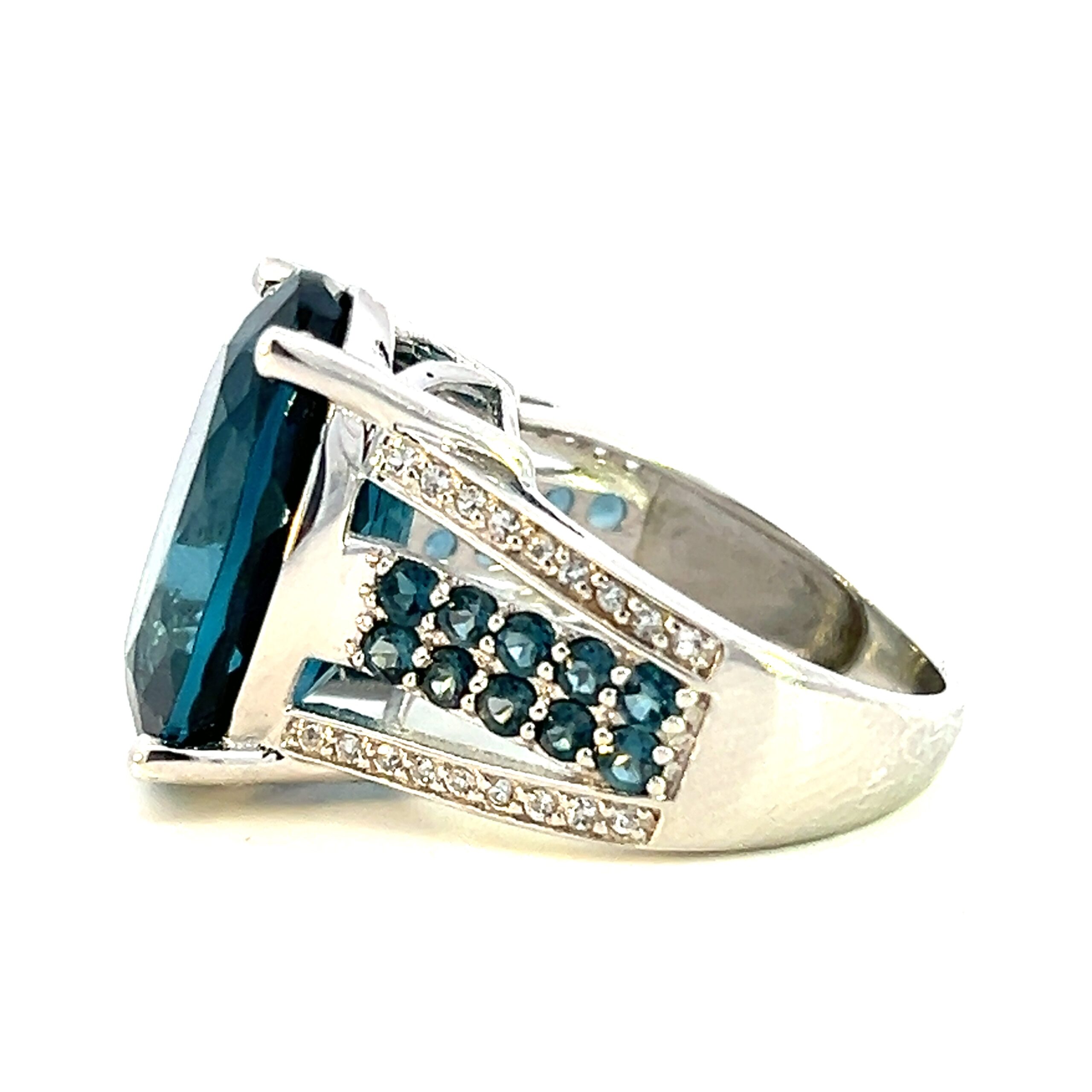 One estate sterling silver London blue topaz ring containing a center 17.5x13mm oval London blue topaz. The ban contains 4 rows of stones including 2 outer rows of 1mm round white sapphires and 2 inner rows of 2mm round London blue topazes. The band has a double split shank that separates the sapphires and topazes.