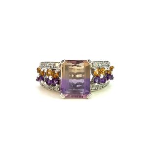 One estate ametrine fashion ring crafted from sterling silver with a center emerald-cut ametrine measuring 8x10mm. The band features 4 rows of gemstones with the outer two rows being 1mm round white sapphires, one inner row being 1.5mm round amethysts, and the other inner row being 1.5mm round citrines.