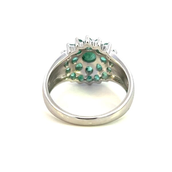 One estate emerald cluster ring crafted from sterling silver containing a center 4mm round emerald and 24 1mm round emeralds in two halos around the center emerald.