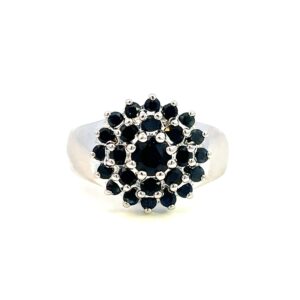One estate blue sapphire cluster ring crafted from sterling silver containing a center 4mm round blue sapphire and 24 2mm round blue sapphire in two halos around the center sapphire.