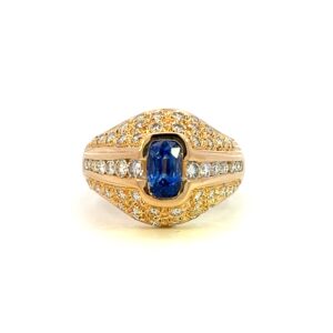 One estate cushion blue sapphire and diamond ring crafted from 18 karat yellow gold with a center elongated cushion-cut violet blue sapphire measuring 6.8x4.3mm and 53 round brilliant diamond weighing 1.15 carats in three rows with the outer two rows covering the other edges of the sapphire. Made in the 1980s.