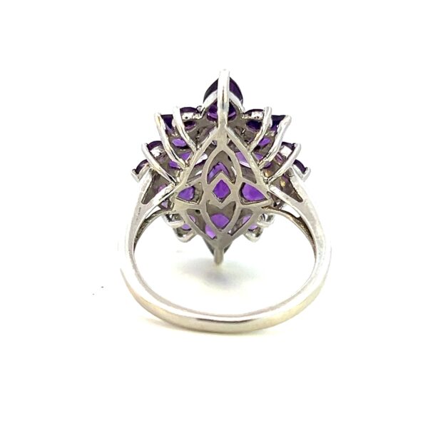 One estate sterling silver amethyst ring containing faceted amethysts in round and pear shapes creating an elongated flower design with points to the north and south.