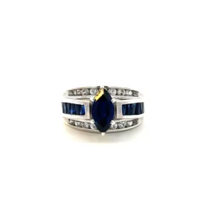 One Estate Lab-Created Blue Sapphire and Diamond Ring crafted from sterling silver with a raised center row set with a center lab-created marquise blue sapphire with 12 lab-created triangle-shaped blue sapphires in a channel settings in the band. The top and bottom rows of the band span the entire front and feature 18 round white sapphires