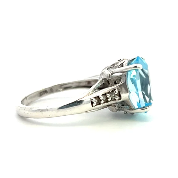 One estate sterling silver ring with a center 12x10mm oval light blue topaz and 6 round white sapphires measuring 1.5mm each bead-set in the band.