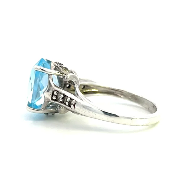 One estate sterling silver ring with a center 12x10mm oval light blue topaz and 6 round white sapphires measuring 1.5mm each bead-set in the band.