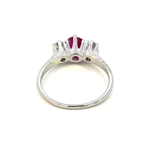 One (1) antique estate 14 karat white three-stone gold ring from 1925 set with a center round faceted 5mm natural ruby and two old mine-cut diamonds weighing 0.50 total carat weight with matching H/I color and I1 clarity. The band is partially accented by an etched wheat leaf design.