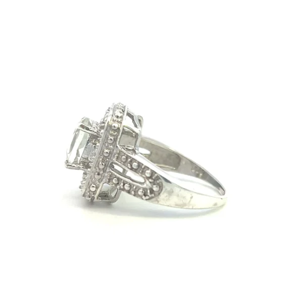 One estate sterling silver fashion ring containing a center oval-shaped faceted light green quartz in a four-prong setting inside an open-style rectangular frame with a split shank band. The frame and shoulders of the band have pave accents designed to mimic melee diamonds.