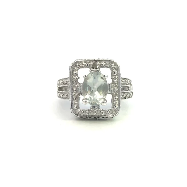 One estate sterling silver fashion ring containing a center oval-shaped faceted light green quartz in a four-prong setting inside an open-style rectangular frame with a split shank band. The frame and shoulders of the band have pave accents designed to mimic melee diamonds.