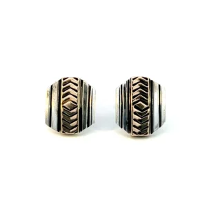 One pair of estate sterling stud earrings with yellow gold-plated accents. The studs feature an elongated hexagon shape with a center stripe of yellow gold-plating accented by a repeating etched chevron pattern. The outer edges of the studs are sterling silver and feature etched vertical lines. Secured with friction posts and backs.
