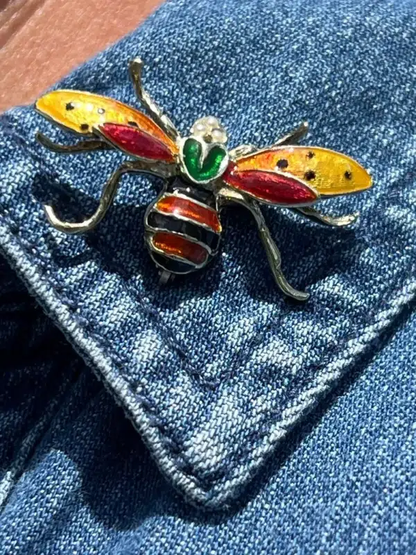 One vintage estate 14 karat yellow gold pearl and enamel insect brooch containing 3 round white pearls measuring 1.6mm each set in the head of an insect. The insect resembles a large hornet, wasp, or bee. the body is coated with several hues of enamel including bright yellow-orange and red in the wings, and a dark green, red, and dark blue or black in the body. The pin measures 20x35mm and is stamped "14K" with a total weight of 5.90 grams. Vintage from the 1960s or 1970s