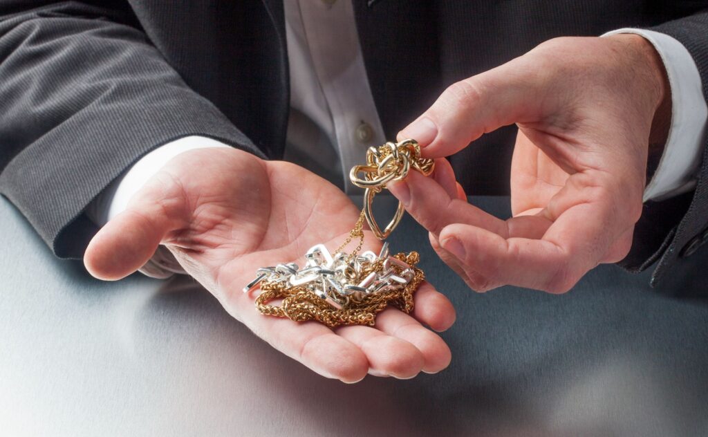 A view of a business man's hands holding a collection of gold jewelry he is considering selling