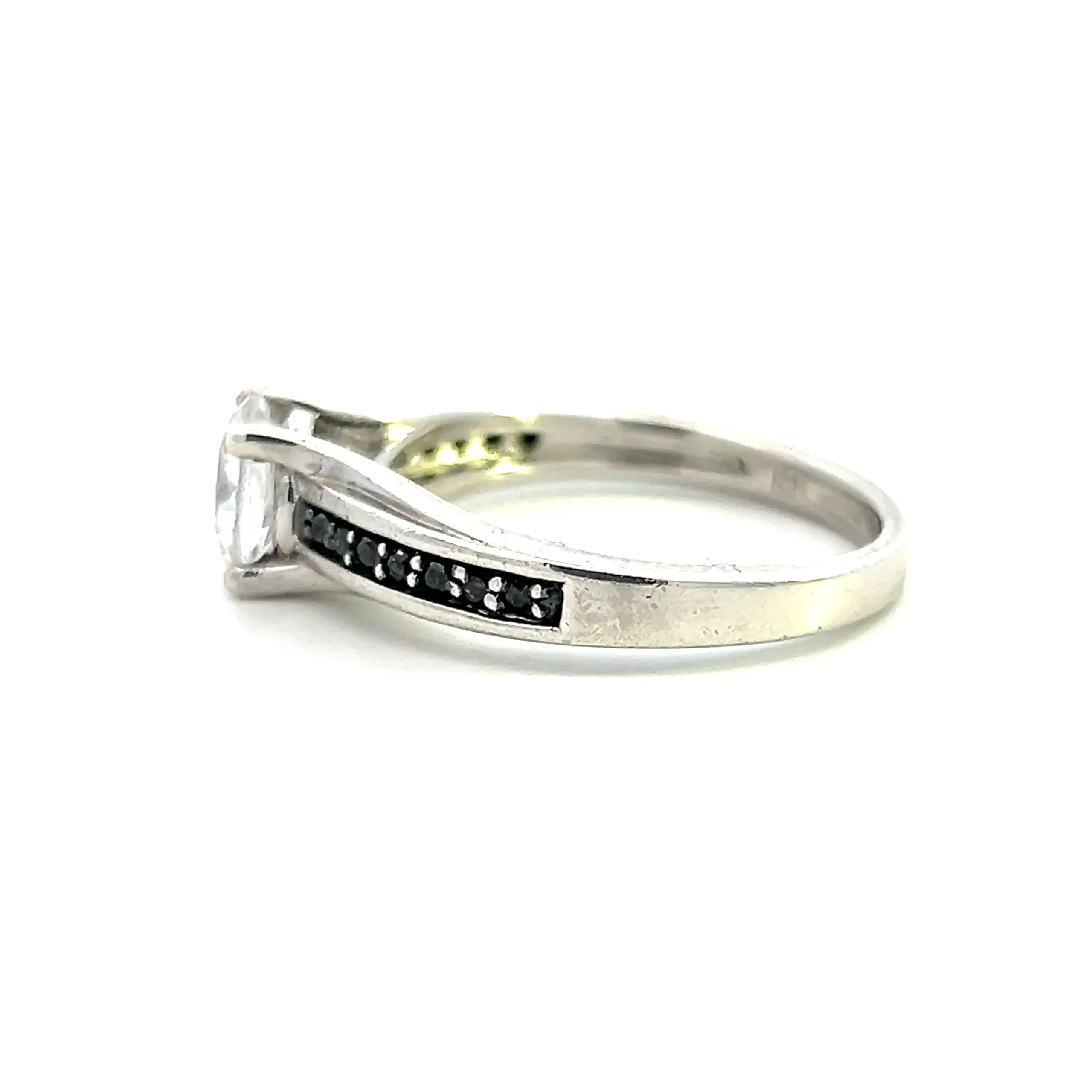 One estate sterling silver ring with a center 6.5mm round white sapphire in a four-prong setting with 14 round black spinel in bead settings in the band with black rhodium plating behind them.