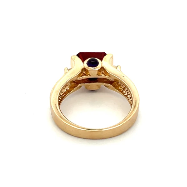 One estate 14 karat yellow gold ring with a center emerald-cut garnet in an east-west tension setting with 2 round brilliant accent diamonds and 2 round accent amethysts