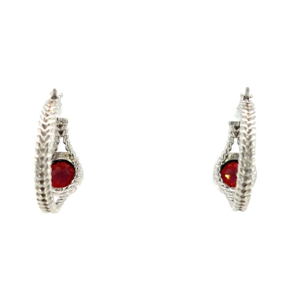 one estate pair of sterling silver hoop earrings with each hoop containing a round faceted garnet measuring 7mm in a bezel setting. the hoops have a rope texture design and a slight split before and after each garnet. the garnet is bezel set in the front of the hoop facing forward