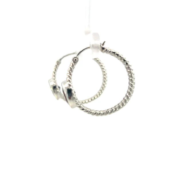 one estate pair of sterling silver hoop earrings with each hoop containing a round faceted garnet measuring 7mm in a bezel setting. the hoops have a rope texture design and a slight split before and after each garnet. the garnet is bezel set in the front of the hoop facing forward