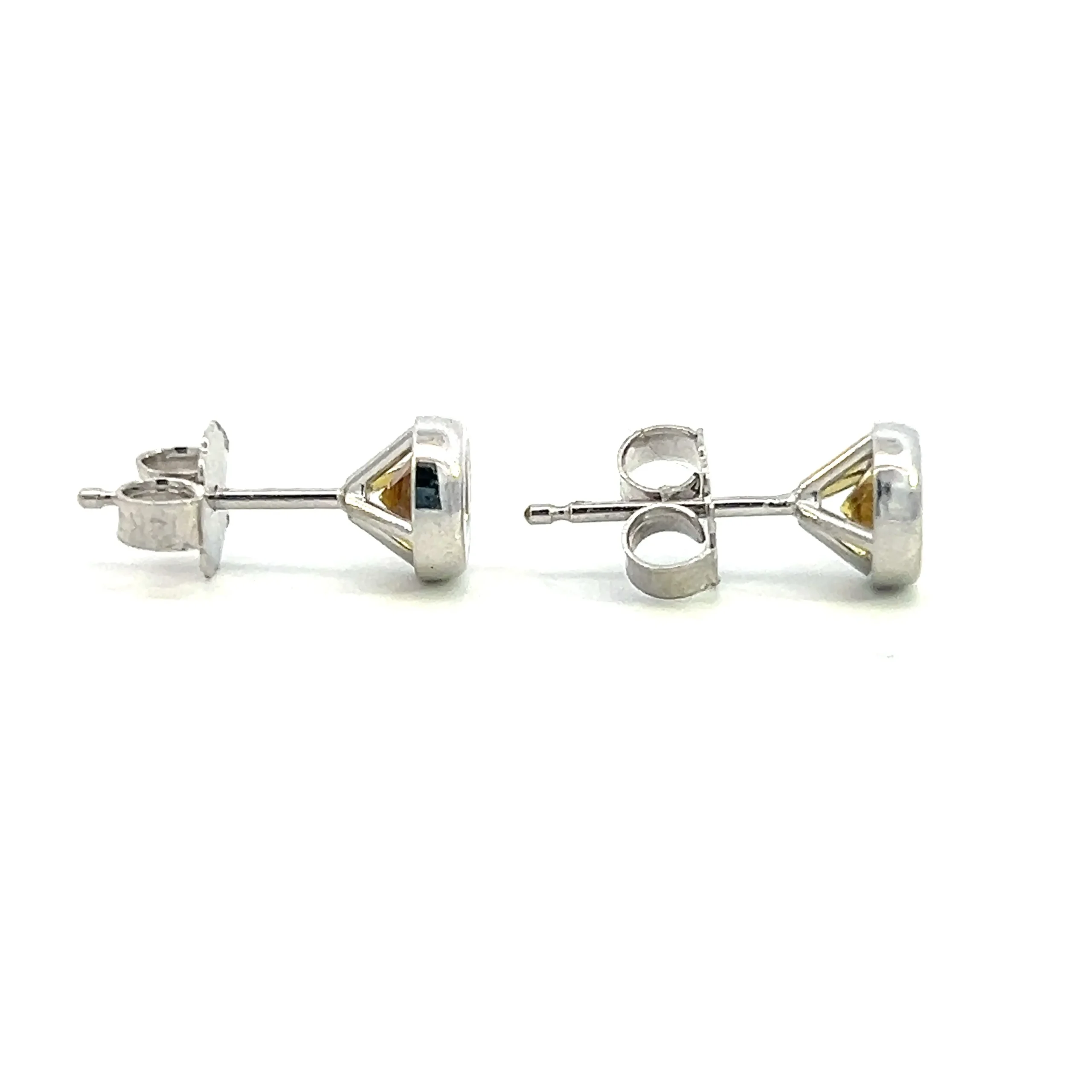 One estate pair of 14 karat white gold gemstone stud earrings containing two round-faceted yellow sapphires weighing 0,84 carat total weight in bezel settings. The earrings are secured with friction posts and backs. Stamped "14K". Total weight of 1.20 grams.