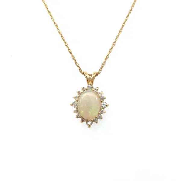 One estate 14 karat yellow gold opal and diamond halo pendant necklace with an oval cabochon opal weighing 0.93 carat and 16 round brilliant diamonds weighing 0.28 carat total weight set in a celestial-inspired scalloped halo design. The pendant is suspended from a 16" rope chain with a spring ring clasp.