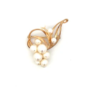 One estate 14 karat yellow god Mikimoto pearl brooch measuring containing 11 pearls with 4 measuring 7mm, 3 measuring 6mm, 1 measuring 5mm, and 3 measuring 4mm. The brooch measures 43x25.73mm and contains tendrils of polished gold resembling organic matter like vines or delicate stems with the 8 of the pearls in a cluster and 3 of them accenting individual tendrils. Vintage from the 1960s. Total weight 8.21 grams. Stamped "MIKIMOTO TOKYO KT4". Secured with a C clasp