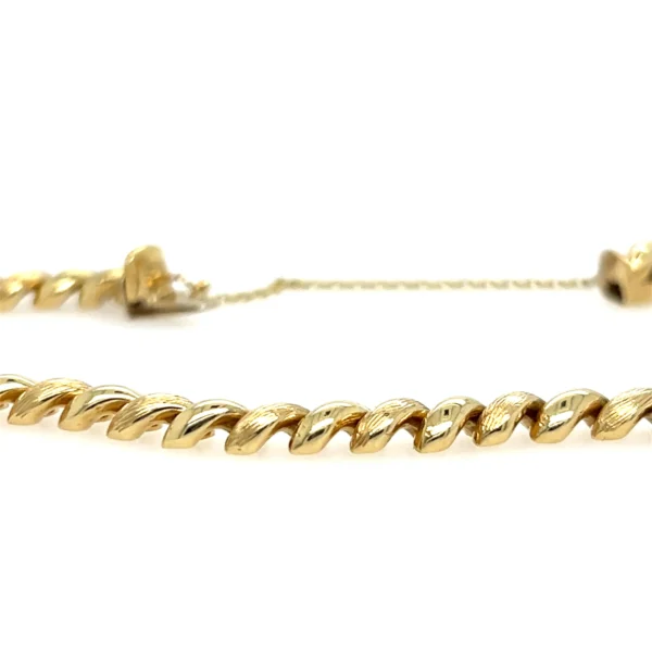 One estate 14 karat yellow gold bracelet with macaroni links that alternate between textured and polished finish. The bracelet measures 7.5" long and is secured with a box clasp with a figure-eight safety catch and a 2.5" safety chain.