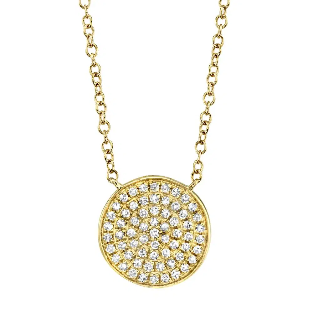 One 14 karat yellow gold disc pendant necklace by Shy Creation with 0.15 carats of round diamonds in pave settings. The pendant is fixed on a 16-18" adjustable chain.