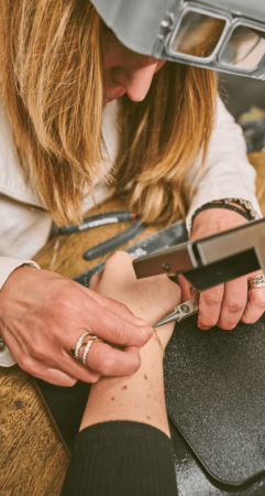 a jeweler welding a permanent bracelet onto a woman's wrist